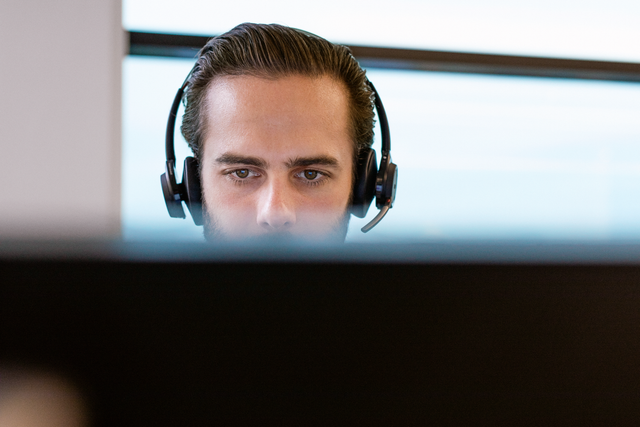 A person wearing a headset while working on a computer.